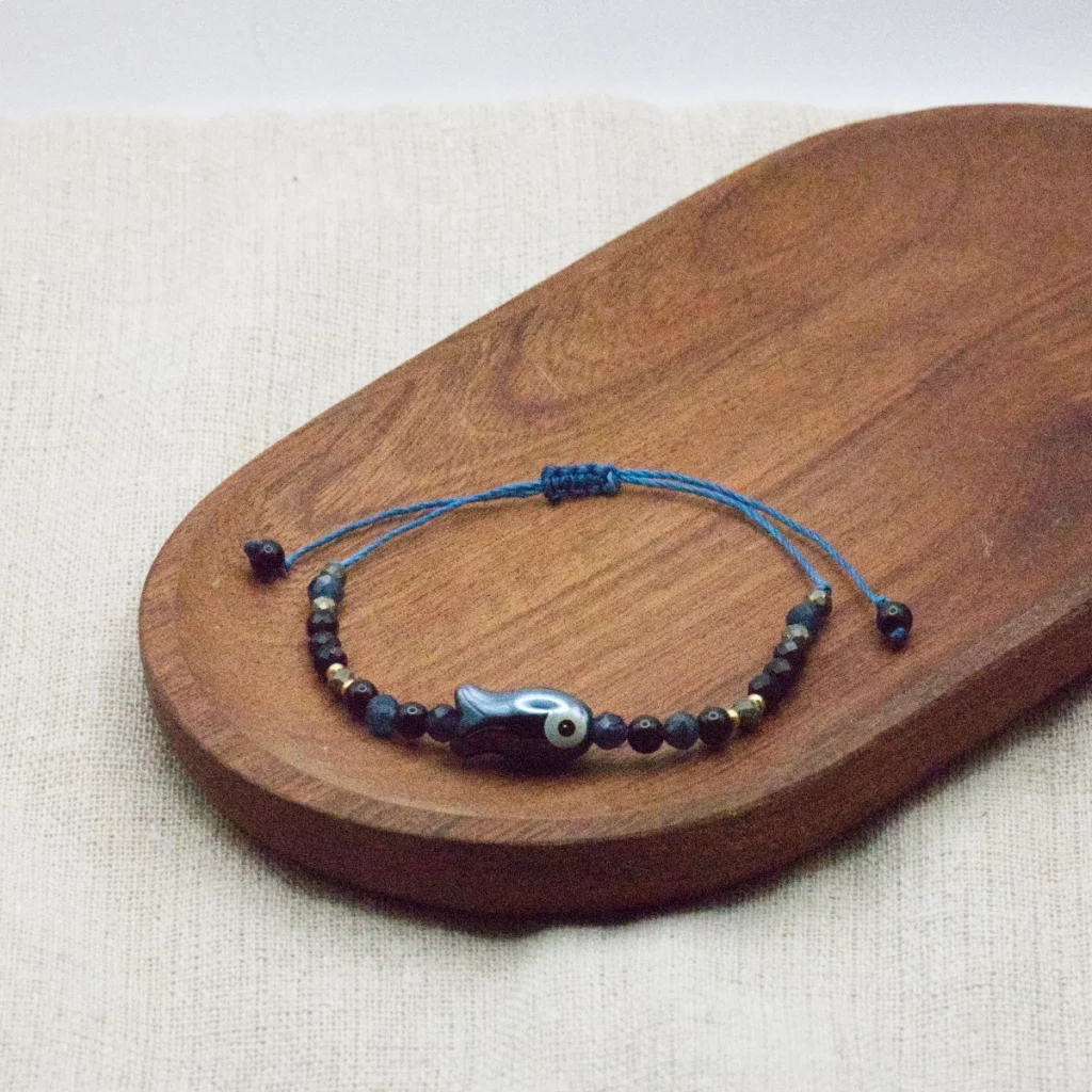 bransoletka z kolekcji kyoto z czarnym agatem onyksem szafirem i rybką z ceramiki na niebieskim sznurku
